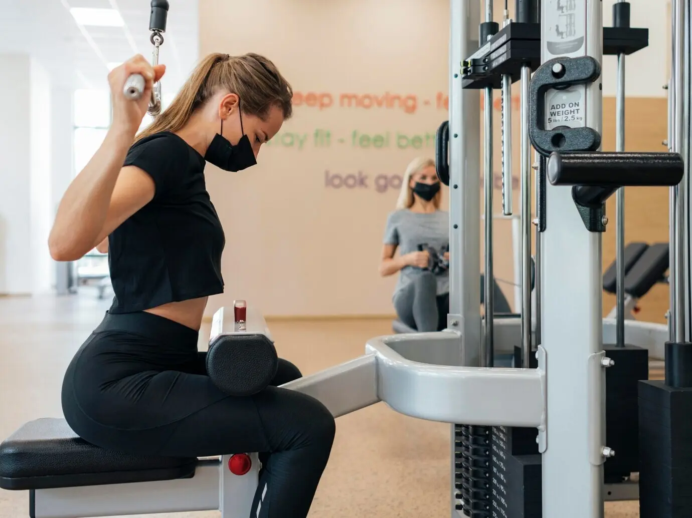 Profile view of a woman exercising at the gym during the pandemic.