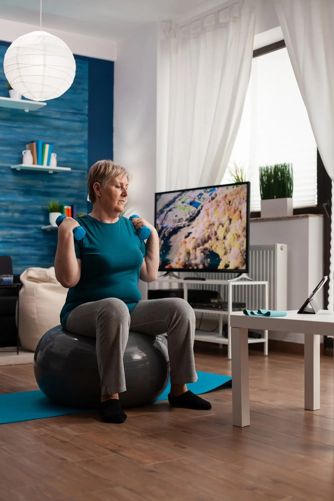 A focused senior man holds dumbbells, exercising to work his muscles and stretch his body.